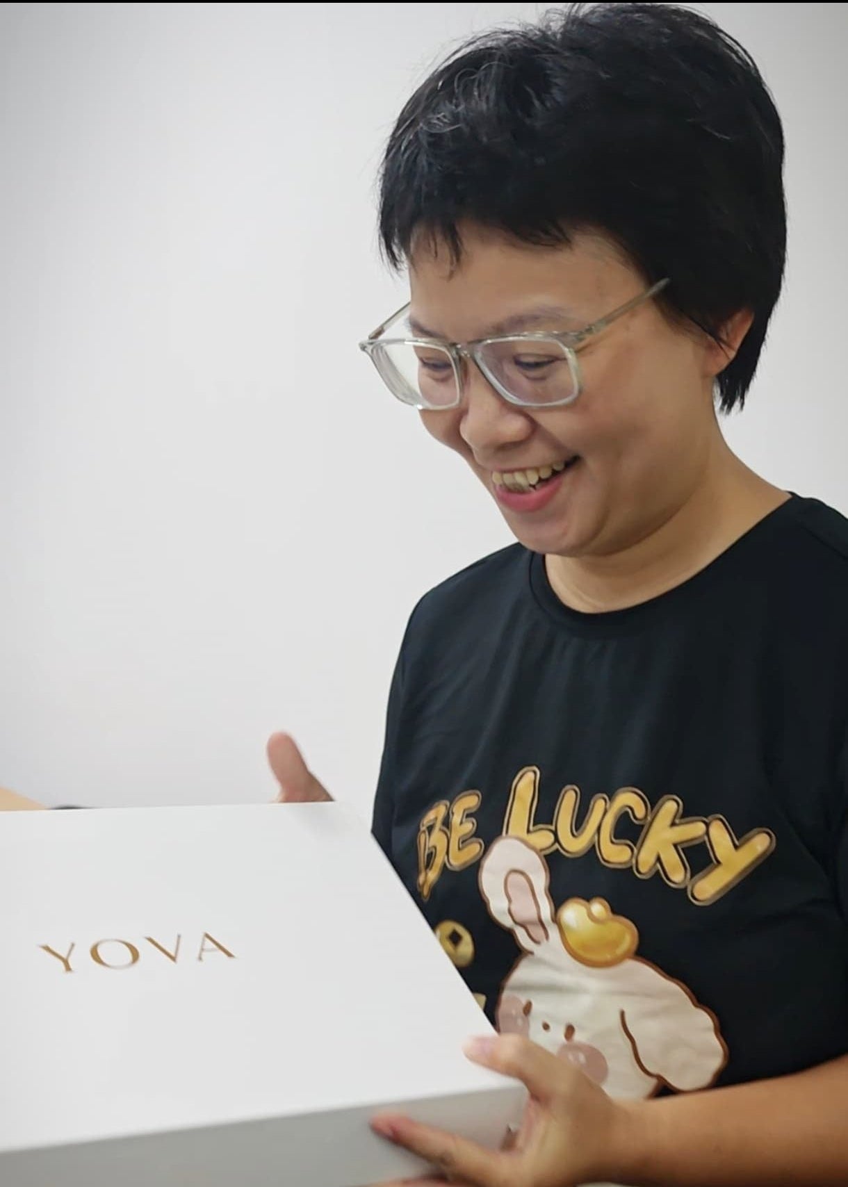 Person holding a white box with 'Yoya' branding, wearing a black t-shirt with a cartoon design.